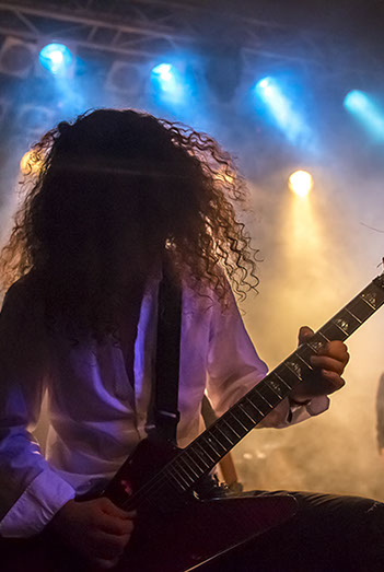 Coast of Madness Gitarrist, steht im Nebel, welcher von Gegenlicht durch leuchtet wird. Der Gitarrist spielt Leidenschaftlich seinen Part